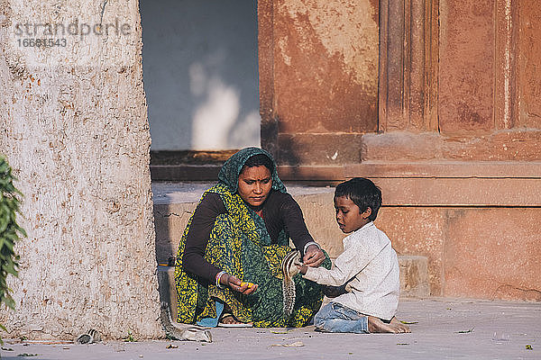 Indische Frau und ihr Sohn füttern ein Eichhörnchenpaar am Agra-Fort.