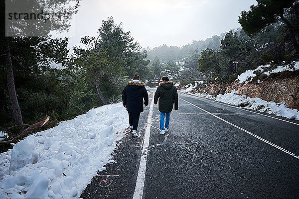 Zwei Freunde gehen eine schneebedeckte Straße entlang