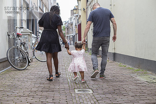 Ein junges Paar geht mit seiner Tochter spazieren