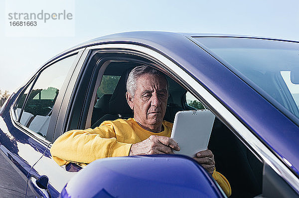 Älterer Mann surft in einem Fahrzeug auf einem Tablet