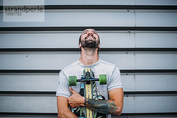 Junge posiert mit Skateboard in der Hand