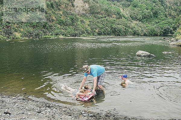 Familie an einer malerischen Flussstelle beim Spielen im Wasser