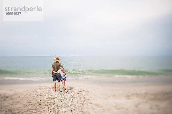 Mann und junges Mädchen stehen mit Blick auf den Ozean in Indialantic FL
