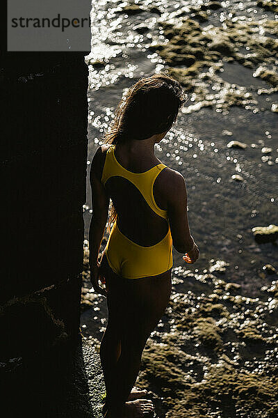 Porträt der schönen lateinischen Frau im gelben Badeanzug am Meer