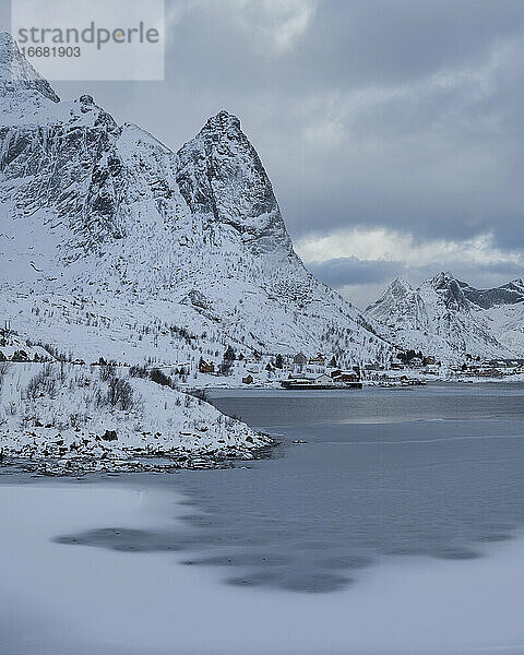 Berge erheben sich über die zugefrorene Bucht im Hafen von Reine  Reine  Moskenesøy  Lofoten  Norwegen