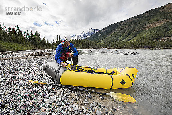 Paddler bläst gelbes Packraft am North Saskatchewan River auf.