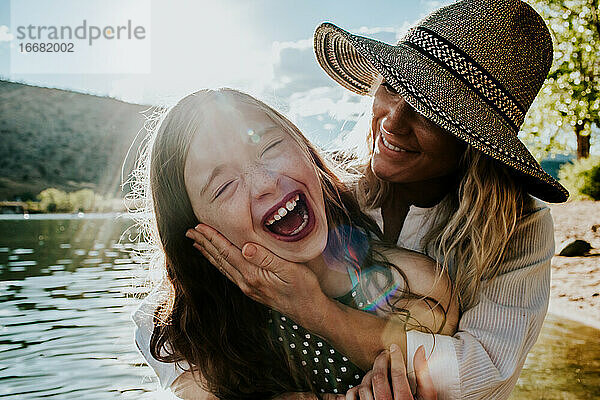 Mutter hält junge glückliche Tochter  während die Tochter lacht