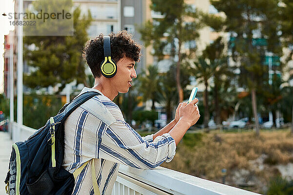 Junger afro-haariger Mann benutzt sein Smartphone und hört Musik
