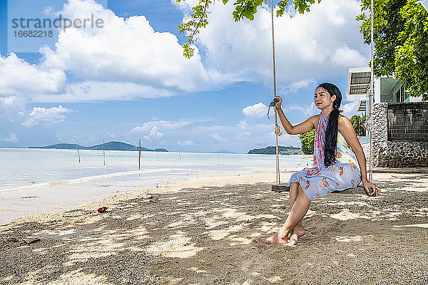 schöne Frau auf einer Schaukel am Strand in Phuket sitzend