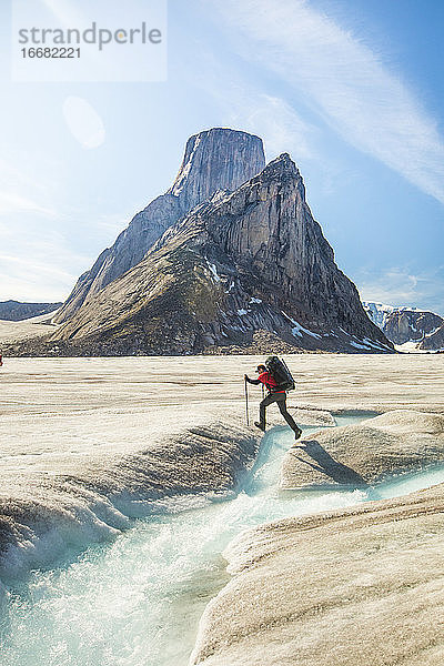 Rucksacktourist wandert über einen Gletscherfluss unterhalb des Mount Asgard  Baffin Island.