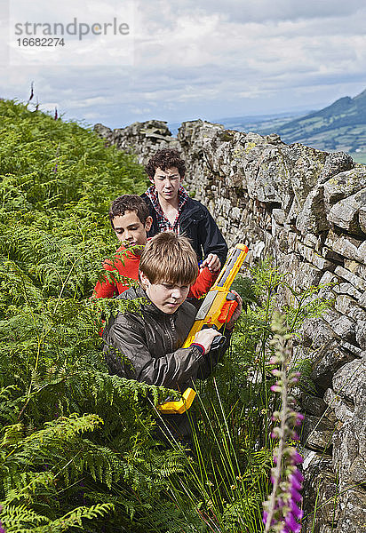 drei Teenager spielen draußen mit ihren Spielzeugpistolen