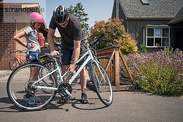 Vater und Tochter tragen Fahrradhelme und bereiten sich auf eine Fahrradtour vor