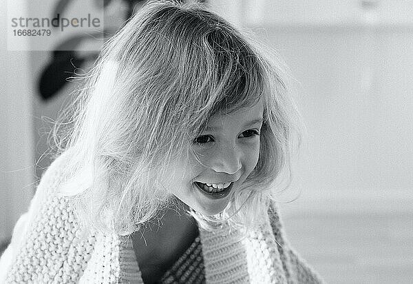 Porträt eines lächelnden und lachenden jungen Mädchens zu Hause