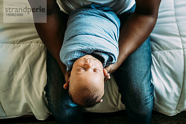 Porträt des schlafenden Babys in den Armen des Vaters von oben