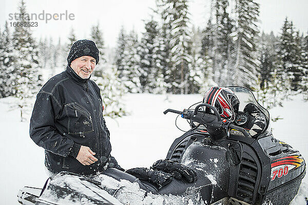 Porträt eines Mannes im Rentenalter beim Schneemobilfahren im Winter.