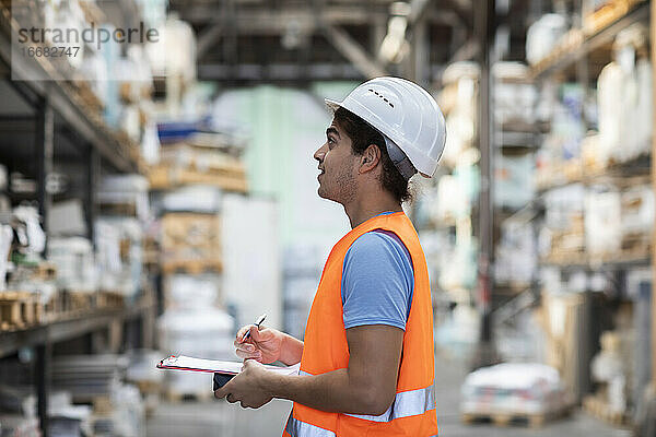 junger Angestellter mit Helm bei der Arbeit in einem Geschäft