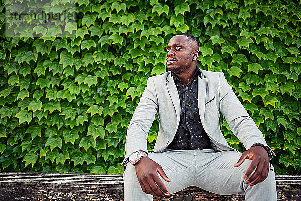 Ein afroamerikanischer Mann sitzt auf einer Parkbank.