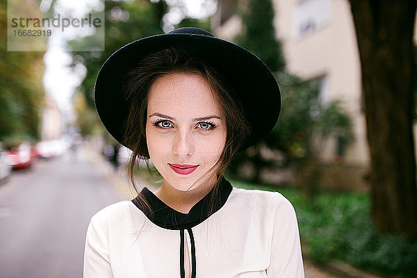 Porträt einer jungen  hübschen Frau mit schwarzem Hut