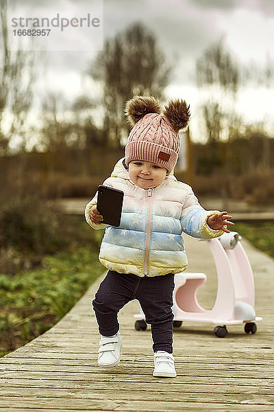 Ein 1 Jahr altes Baby-Mädchen ist mit einem rosa Motorrad draußen