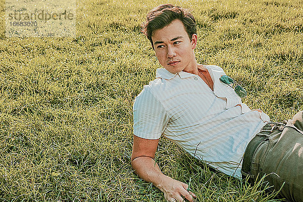 Porträt eines jungen Mannes  der im Gras sitzt.
