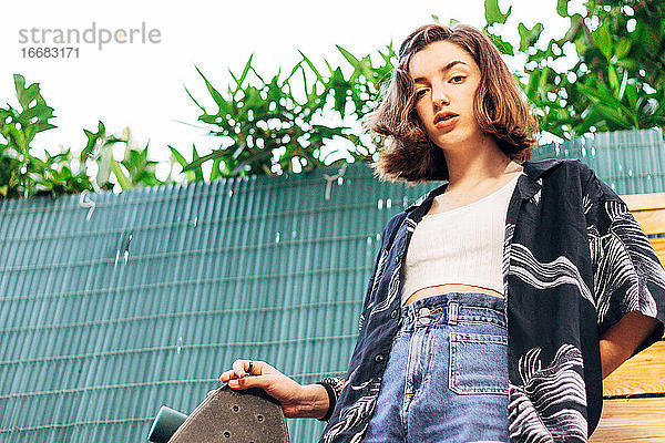 Teenager-Mädchen mit Longboard und Hawaii-Hemd