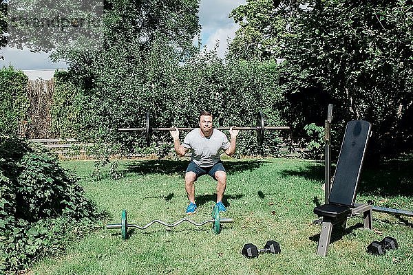 Mann trainiert zu Hause im Garten mit seinem Fitnessgerät
