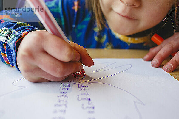 Nahaufnahme eines kleinen Mädchens  das mit einem bunten Marker auf Papier zeichnet