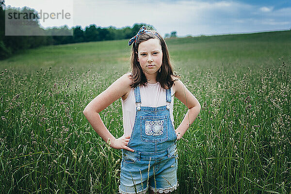 Teen Girl in Overall Shorts Standing in Grassy Field in the Midwest