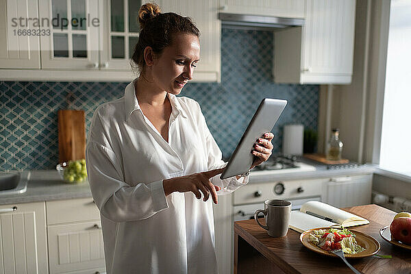 Geschäftsfrau  die beim Frühstück auf einem Tablet surft