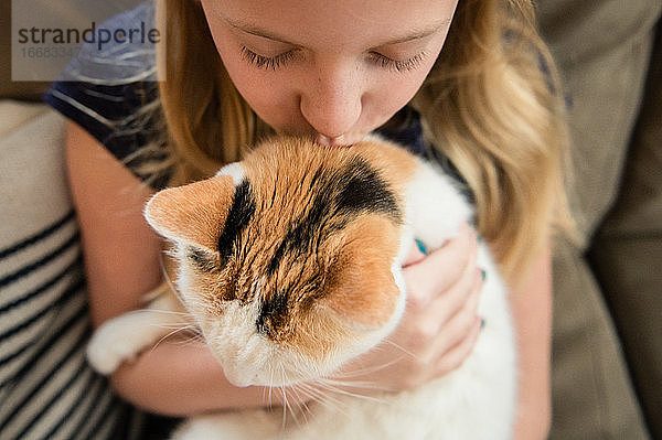 Nahaufnahme eines jungen Mädchens  das eine Hauskatze küsst