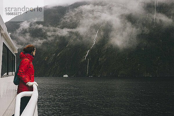 Eine Frau starrt auf die umliegenden Berge im Milford Sound  Neuseeland
