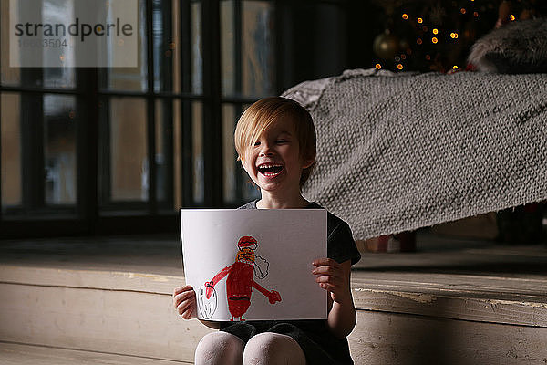 Ein fröhliches Mädchen hat den Weihnachtsmann gemalt.