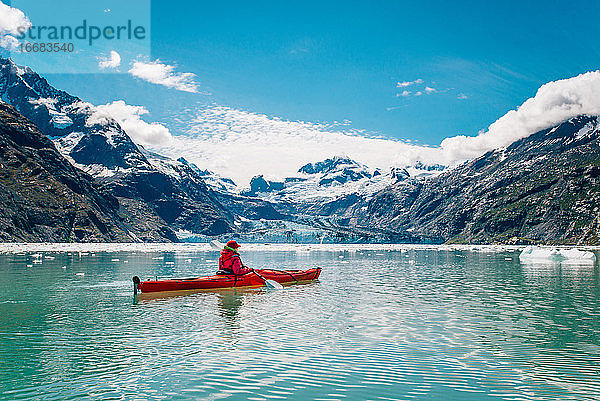Frau beim Kajakfahren im Glacier Bay National Park mit Gletscher im Hintergrund