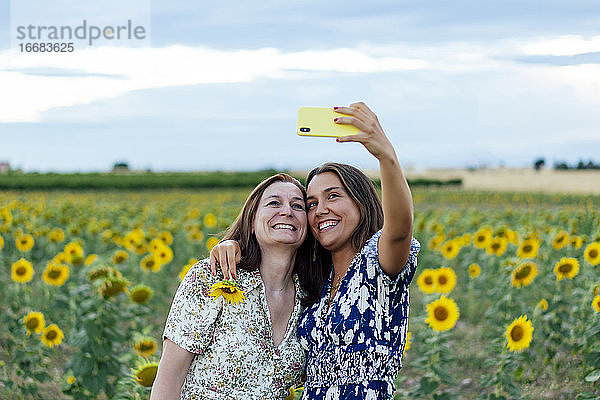 Mutter und Tochter umarmen sich und machen ein Foto mit dem Smartphone