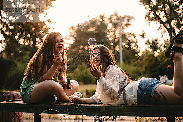 Glückliche lesbische Paar spielt mit Blasen im Park im Sommer entspannen