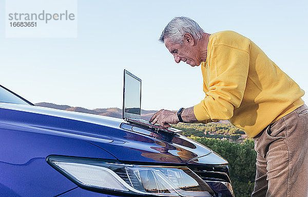 Älterer Mann benutzt Laptop im Auto
