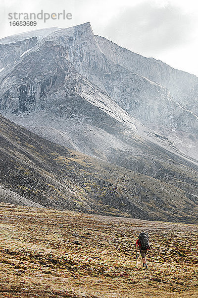 Rucksacktourist beim Wandern unterhalb des massiven Granitgipfels am Akshayak-Pass