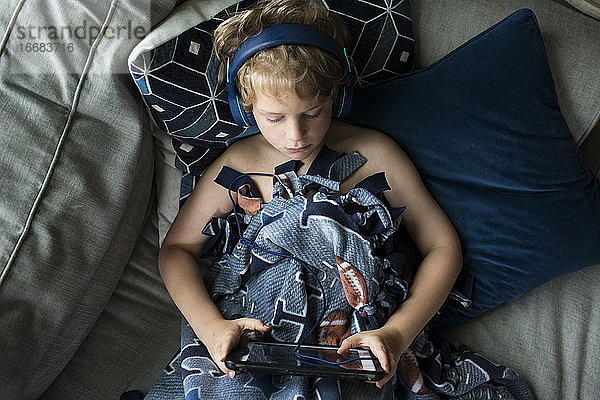 Draufsicht auf einen jungen Jungen mit Kopfhörern auf einem Tablet-Computer