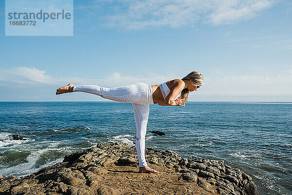 Junge Frau übt Yoga am Strand
