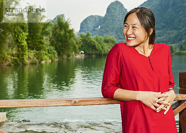 schöne Frau  die ihre Ellbogen auf die Brüstung neben dem Fluss Li stützt