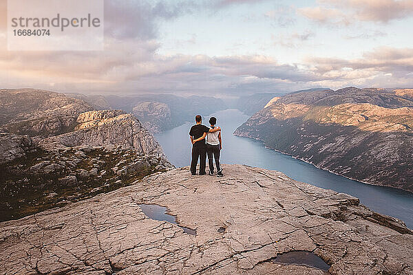 Paar steht bei Sonnenuntergang auf der Klippe am Preikestolen  Norwegen