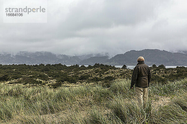 Ein älterer Mann blickt auf eine seichte Bucht.