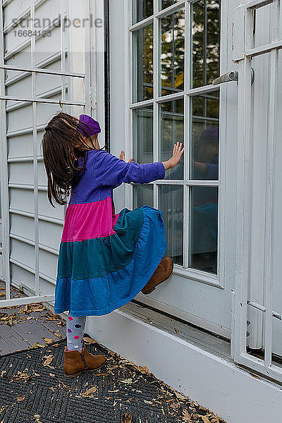 Kleines Mädchen wartet mit Gesichtsmaske ungeduldig an der Tür