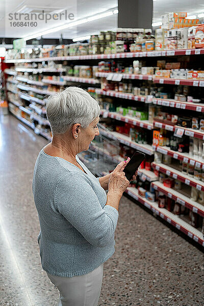 Kaukasische ältere Frau mit weißen Haaren beim Einkaufen im Supermarkt
