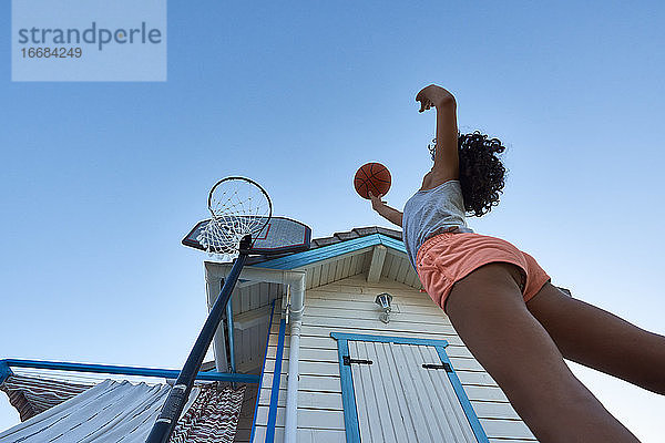 Ein Mädchen wirft einen Korb auf ihrem eigenen Basketballplatz von unten