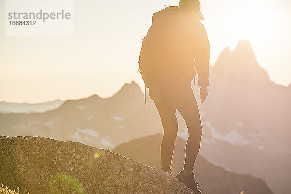 Scherenschnittansicht eines Rucksacktouristen  der auf einem Berggipfel unterwegs ist.