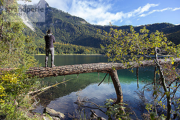 Eine Person blickt an einem sonnigen Tag in Deutschland auf einen klaren Alpensee