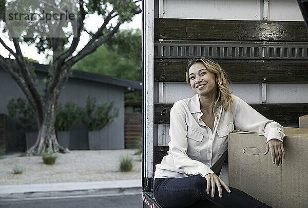 Frau sitzt in einem Umzugswagen mit Kisten