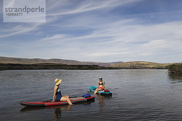 Zwei Freundinnen sitzen auf ihren SUPs auf dem Columbia River in Oregon.