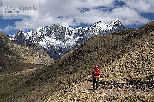 Eine Person wandert mit Stöcken auf einem Pfad in der Cordillera Huayhuash